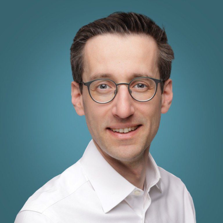 Praxisarzt Jihannes Matschke , Neutral gekleideter Mann mit kurzem Haar und einem ernsthaften Blick vor einfarbigem Hintergrund.